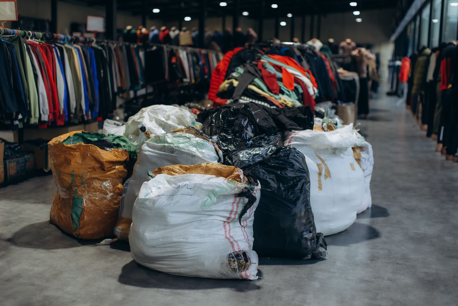 Bagged clothing stacked at a textile sorting warehouse.