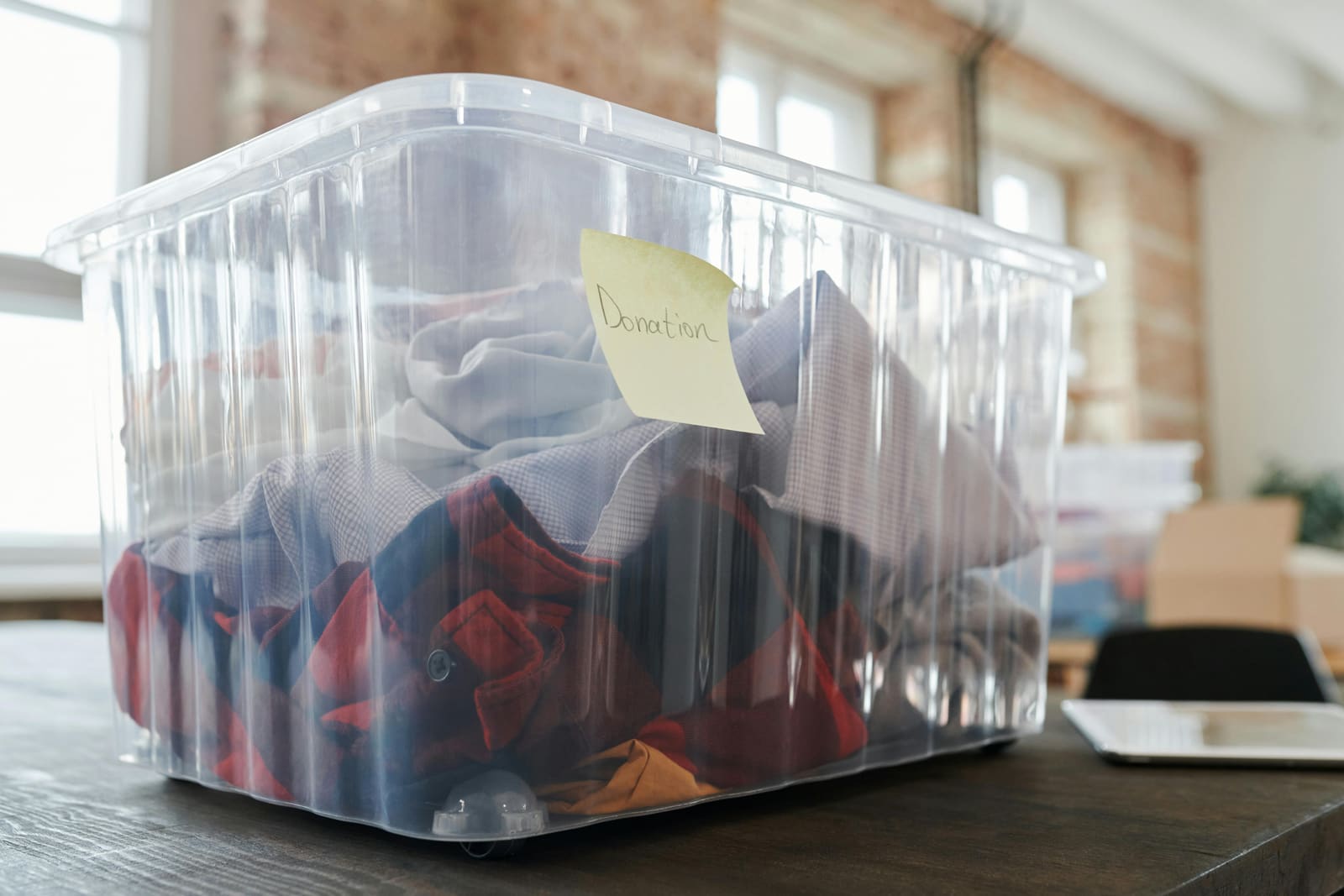 Clear donation bin with a branded label, photographed in studio.