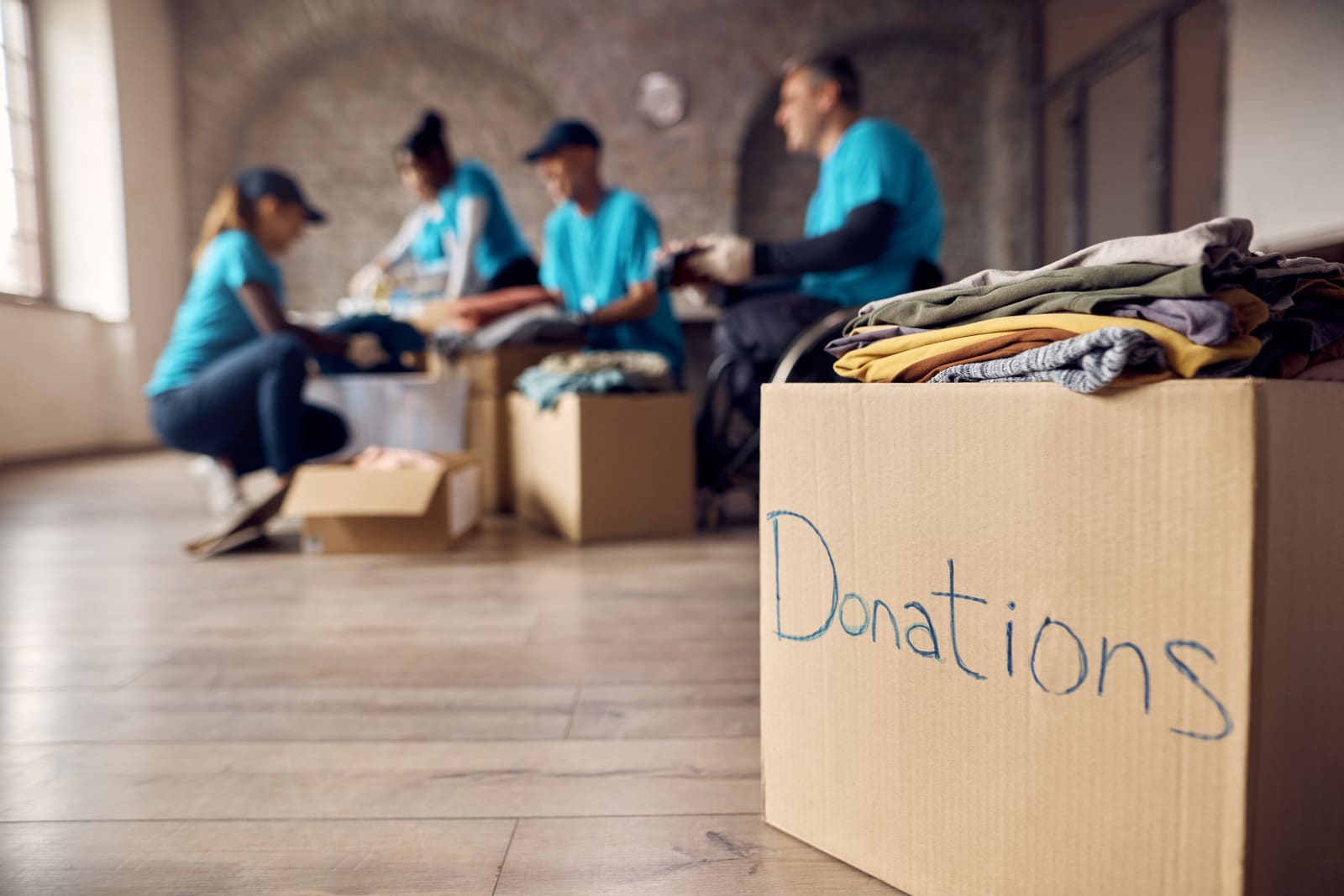 Hands placing clothing into a donation box.